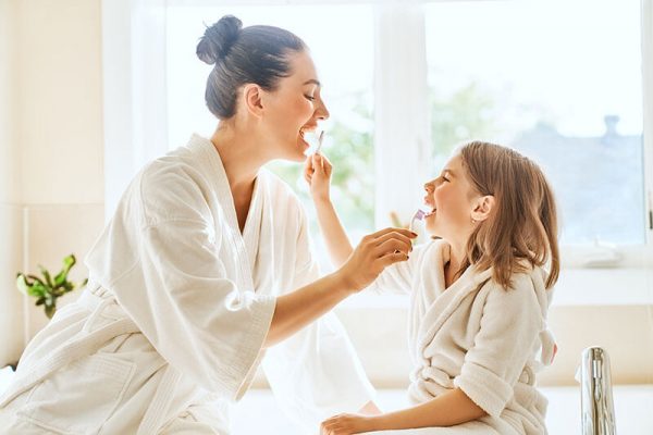 mother and daughter brushing their teeth