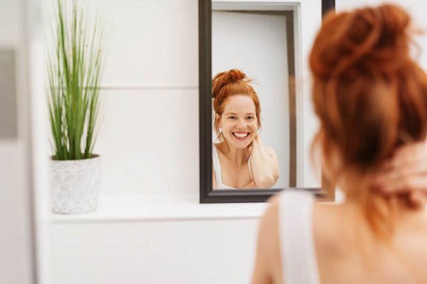 redhead woman smiling in the mirror