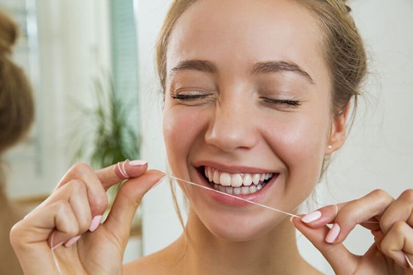 woman flossing her teeth at home