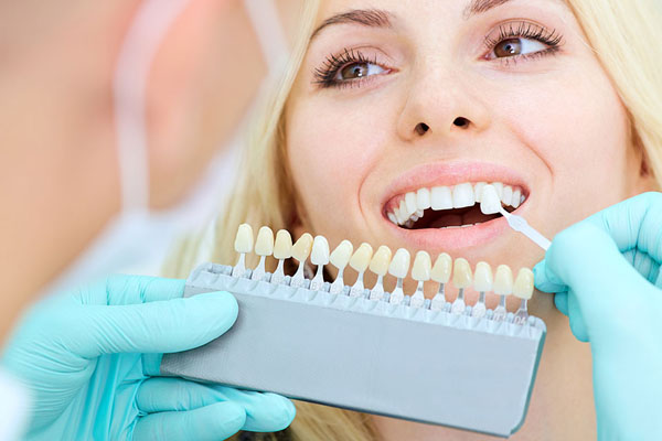 dentist compares dental veneer to natural tooth